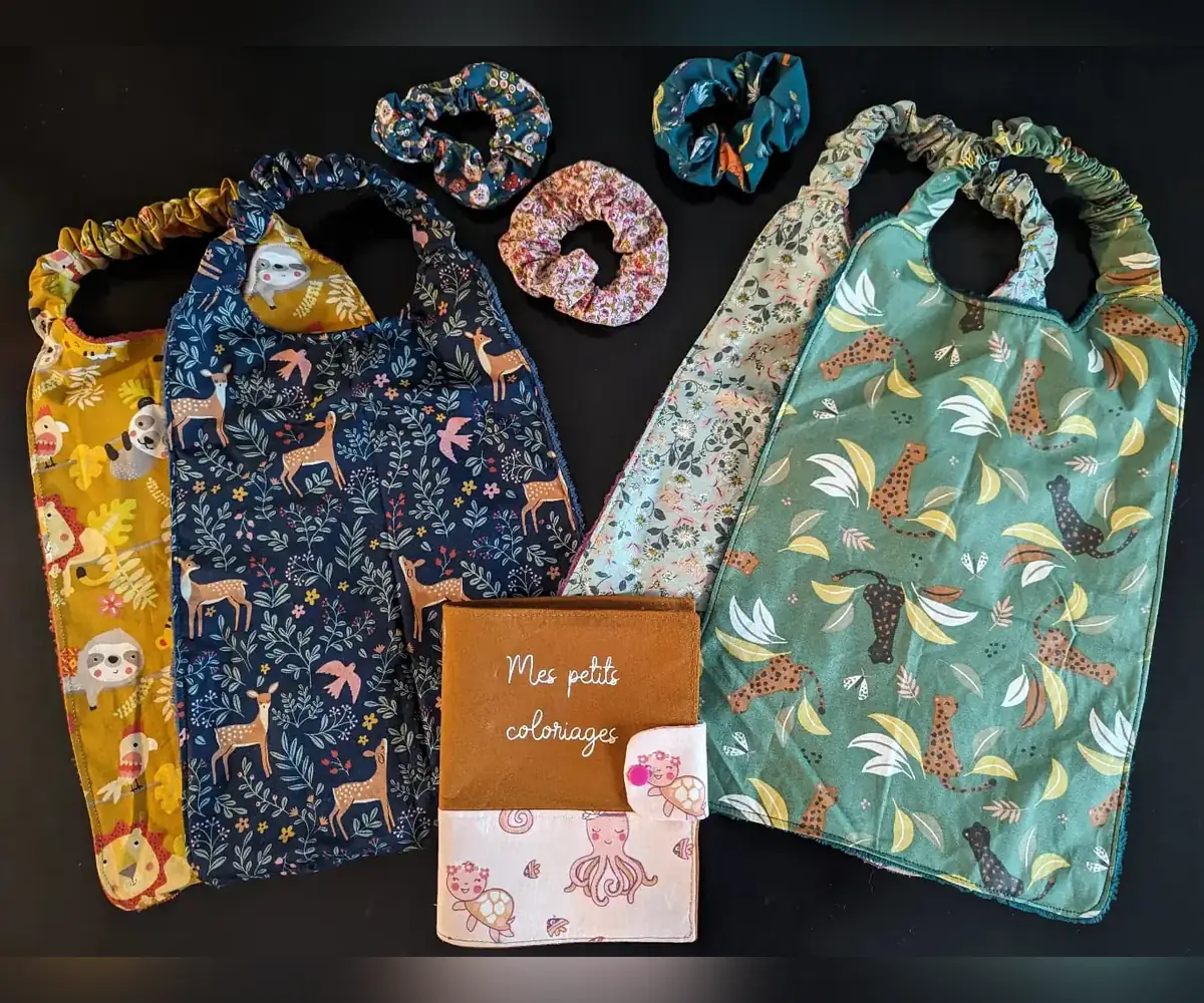 Sac à dos animalier, tablier renard, bavoir dinosaures, carnet à colorier avec crayons, carnet alphabet, pochette dent de lait et protège-carnet étoilé.